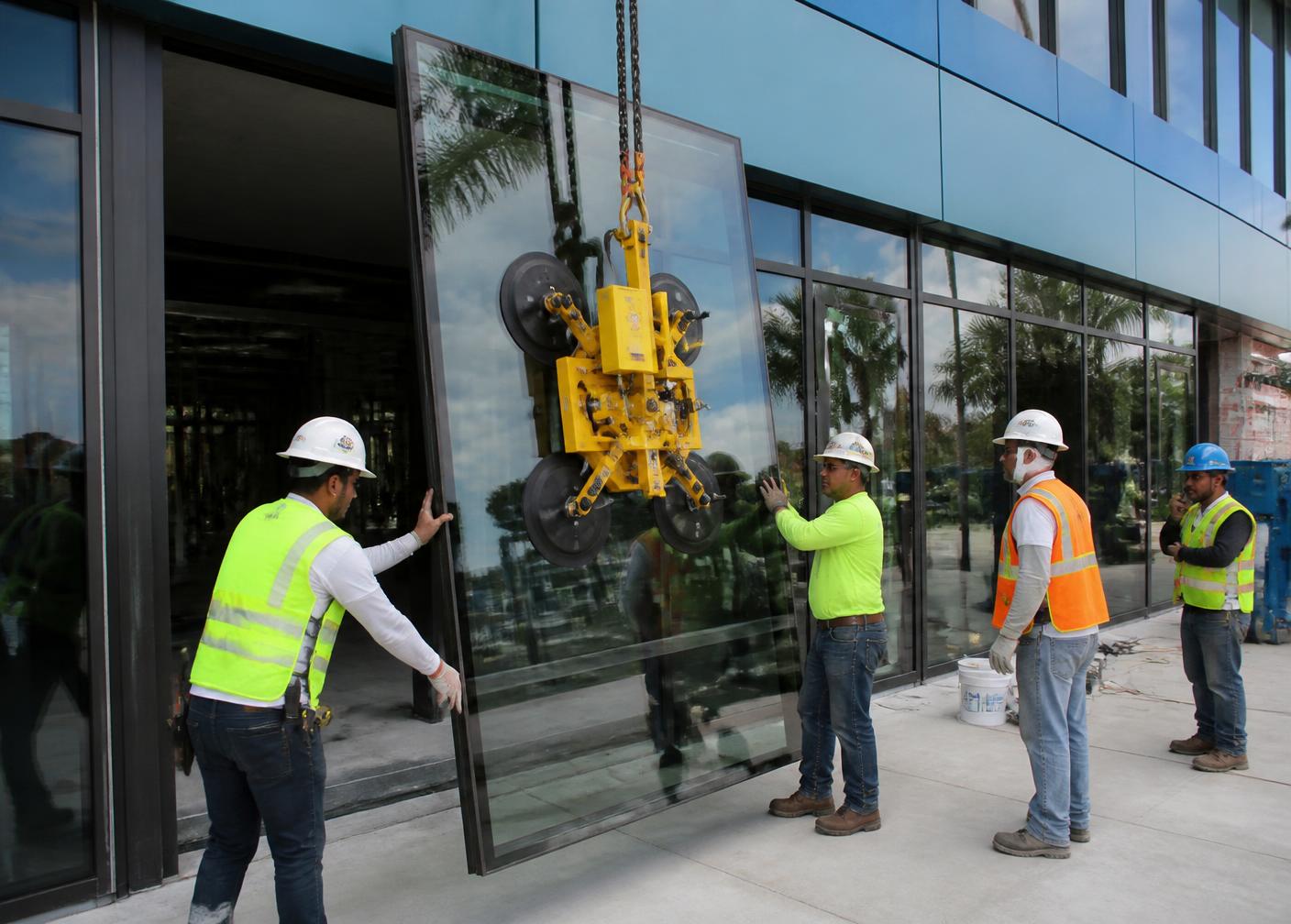 Glaziers setting an impact-rated storefront glass panel on a South Florida commercial building